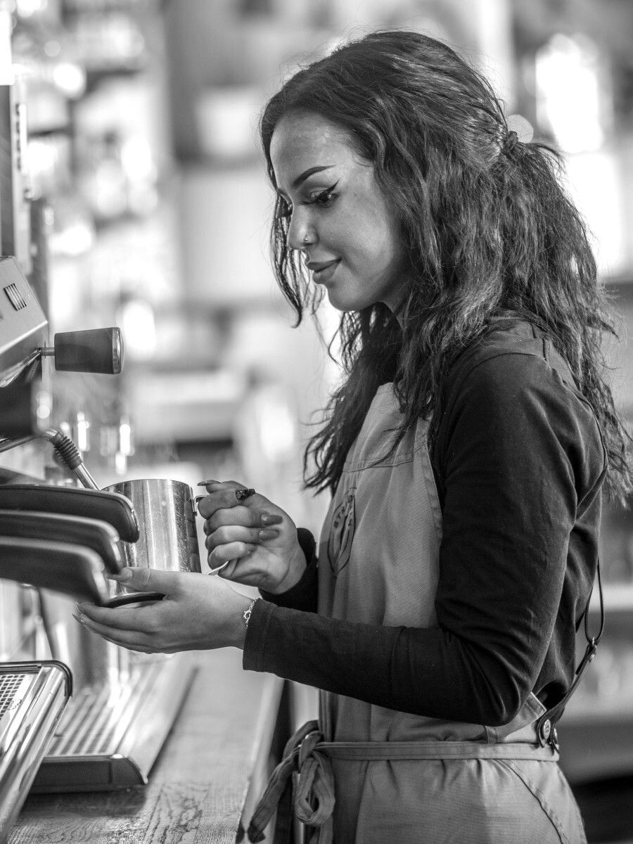 Barista skummar mjölk vid espressomaskinen på Café Strandgatan